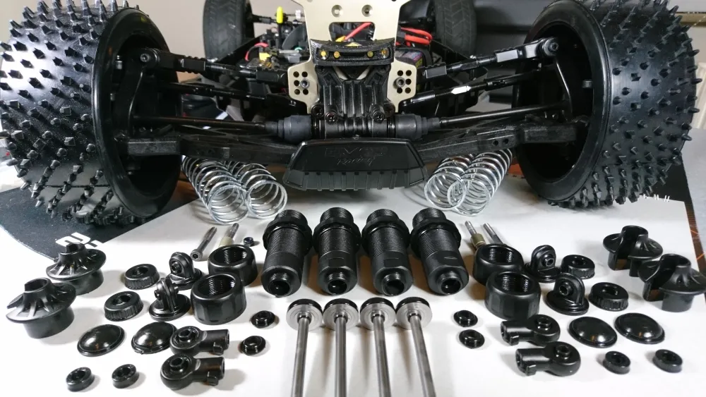 MCD RR5 Competition Buggy, zerlegte Stoßdämpfer mit Federn, Kolbenstangen und Befestigungsteilen vor dem Fahrzeug