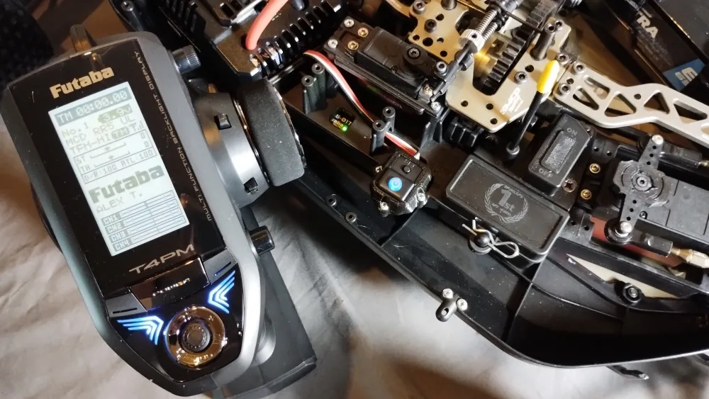 Futaba-Pistolensender mit eingeschaltetem Display neben der Elektronik des MCD RR5 Max 4 Ultimate