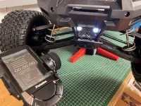 Weiß leuchtende Position-Light-Frontleuchte am Traxxas X-Maxx neben einer Stoppuhr auf dem Senderdisplay