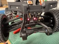 Rot leuchtende Position-Light-Rückleuchte an der freiliegenden Hinterachse eines Traxxas X-Maxx auf einem Montageständer