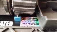 Montierte Ritzelabdeckung neben dem Motor und einem Team-Associated-Aufkleber im SR7-Chassis