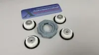 Vier weiße Fahrwerkseinsätze mit Metallmitte, O-Ringen und grauem Ringwerkzeug für Traxxas X-Maxx, schräg von oben